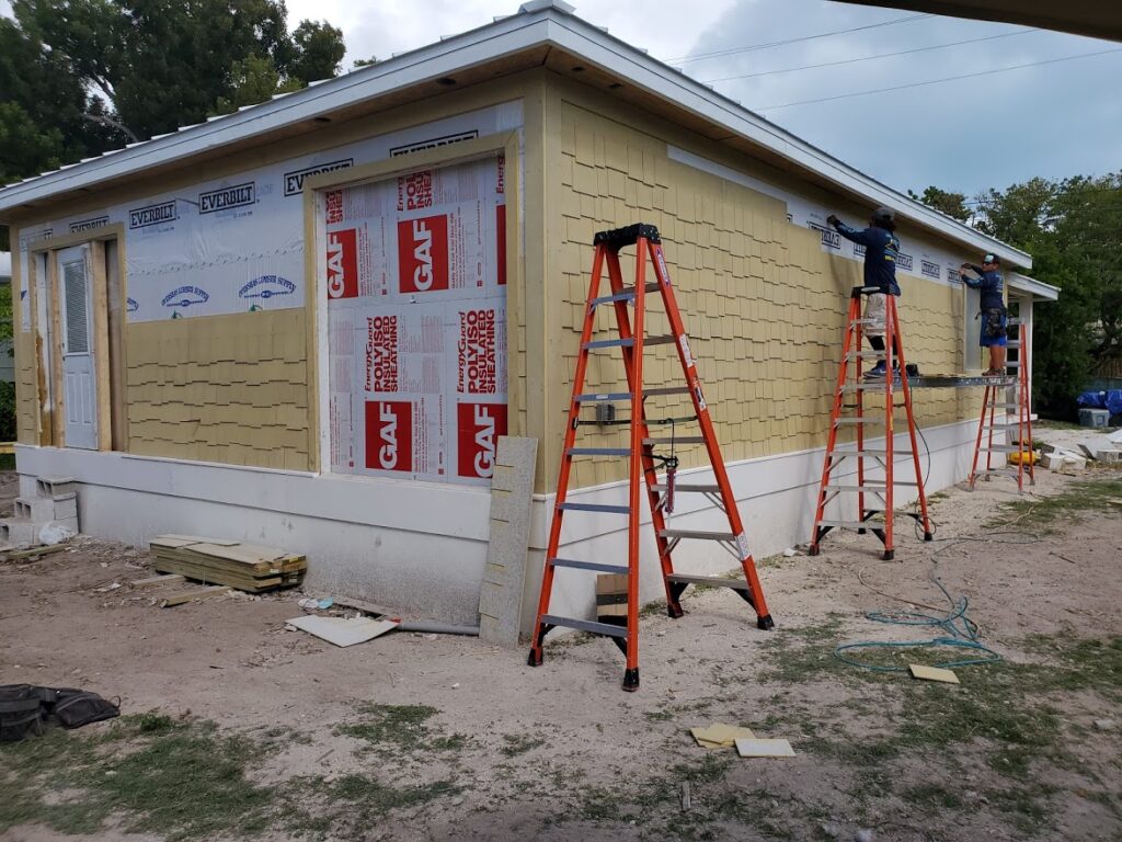 House exterior with workers installing wall insulation and roofing prep