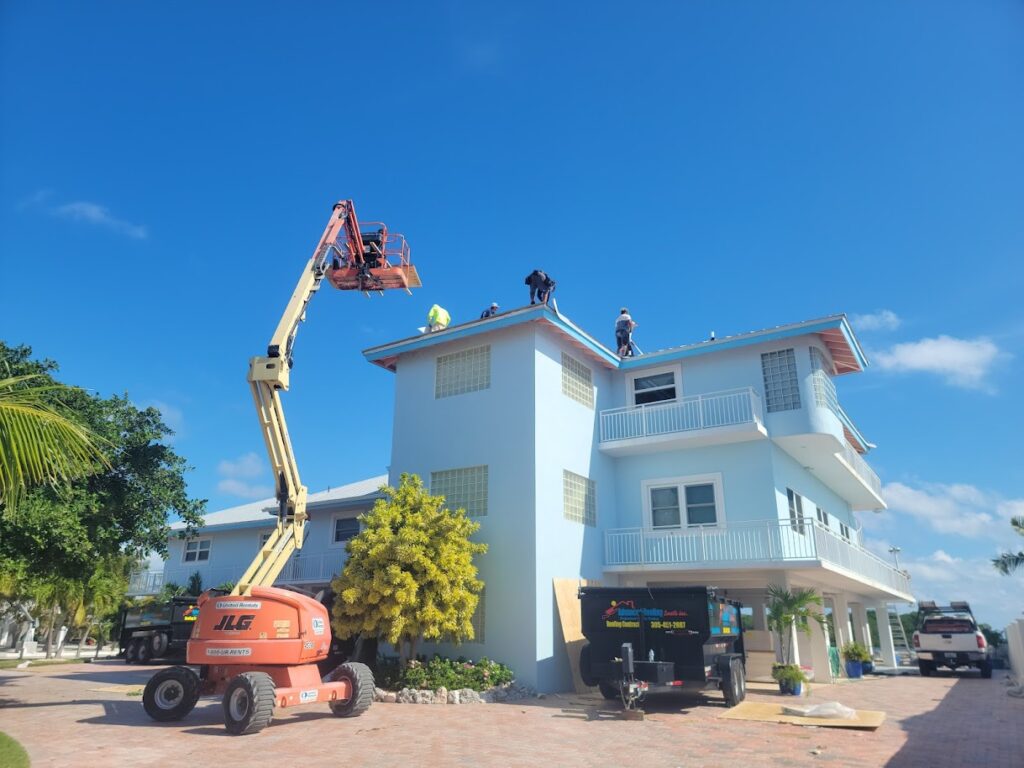 Roofing crew installing roof on coastal home using boom lift equipment