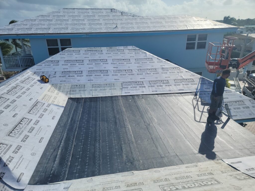 Worker installing roof underlayment with lift on residential roof