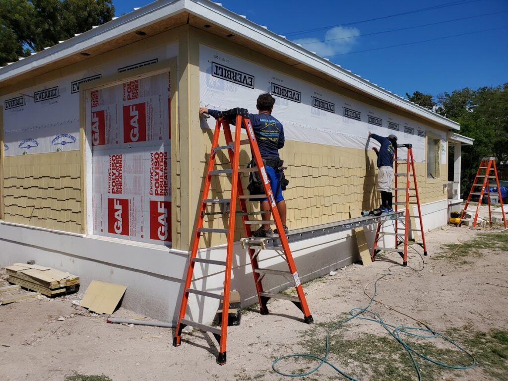 Workers installing exterior wall and roofing materials